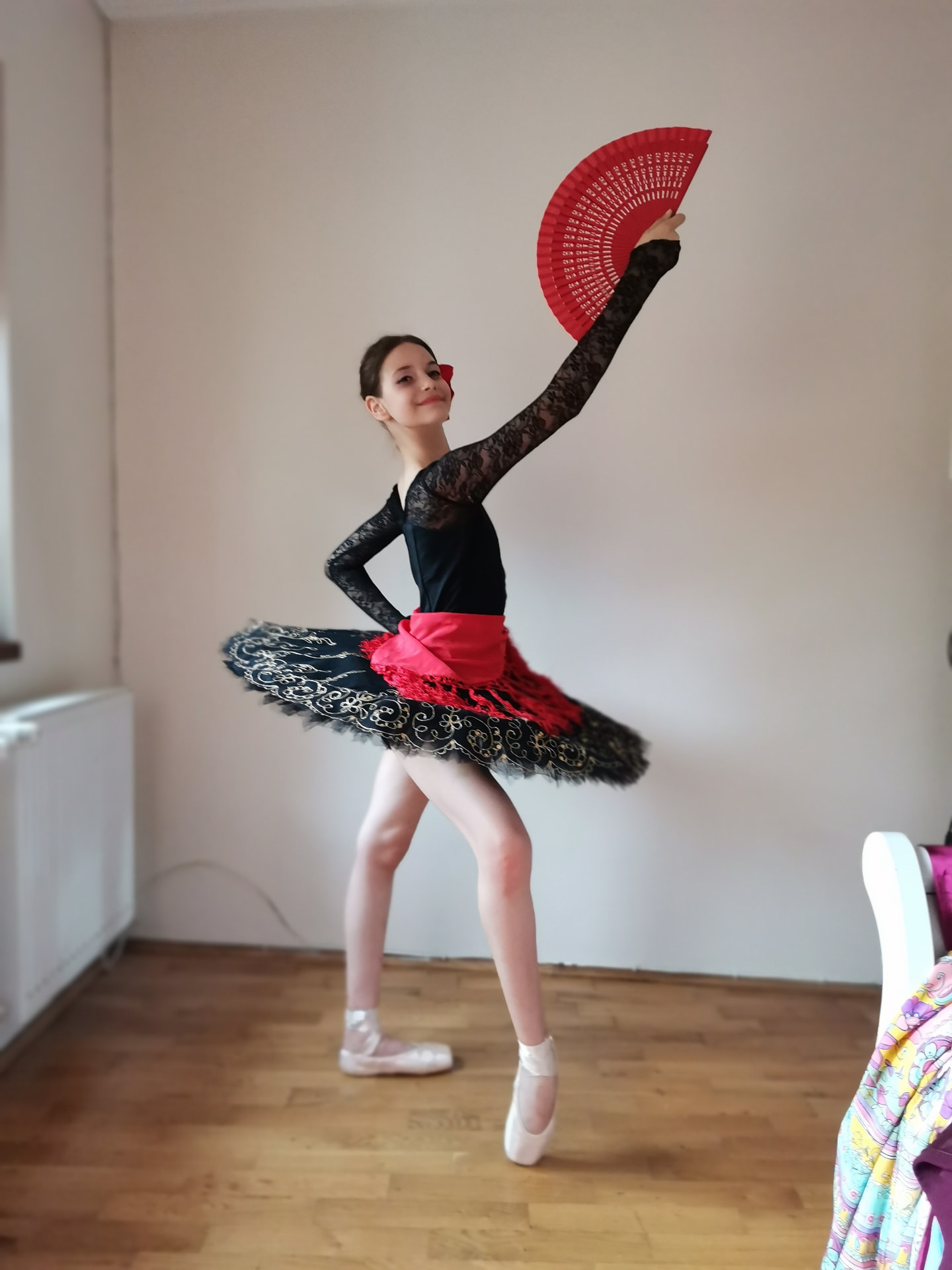 Balerină în poante cu tutu negru și evantai roșu