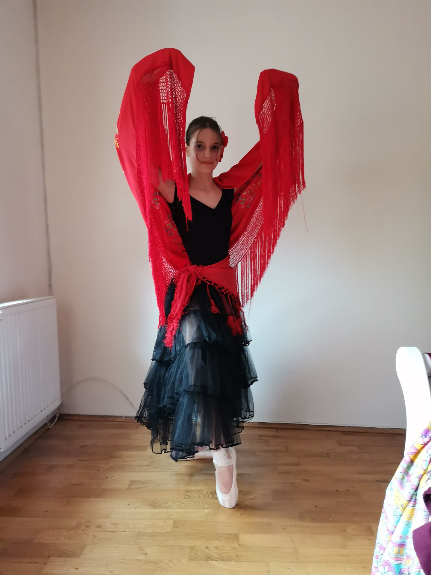 Tânără dansatoare ridicând artistic un șal roșu cu franjuri